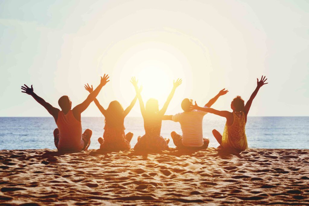 Five friends raising their arms on the sand at sunset in Myrtle Beach