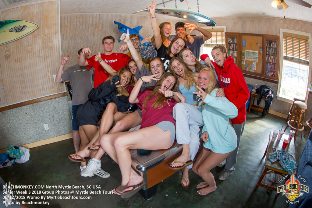 Senior Week group smiling on a bench inside a North Myrtle Beach rental