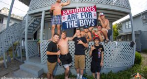 Senior Week guys posing on a North Myrtle Beach rental porch with a banner