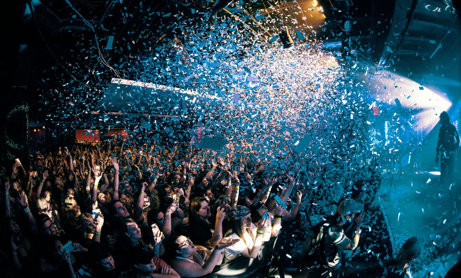 Crowd cheering under falling confetti at a Senior Week party