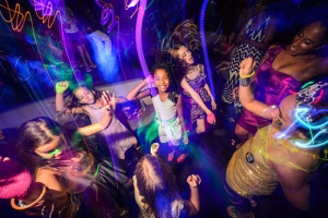 Friends dancing under neon light trails at a Senior Week glow party