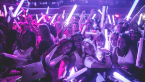 Crowd waving light sticks at a Senior Week glow party