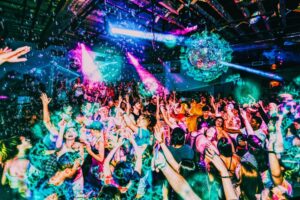 Grads dancing under disco balls and confetti at a Senior Week party