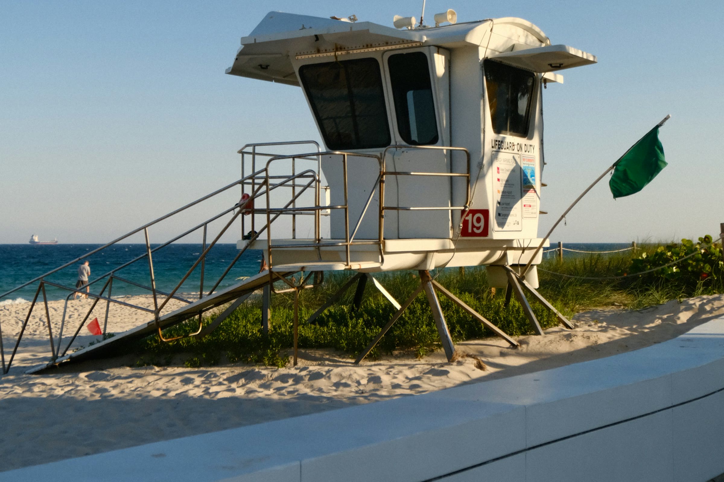 Lifeguard stand on the beach with a green warning flag flying at sunset