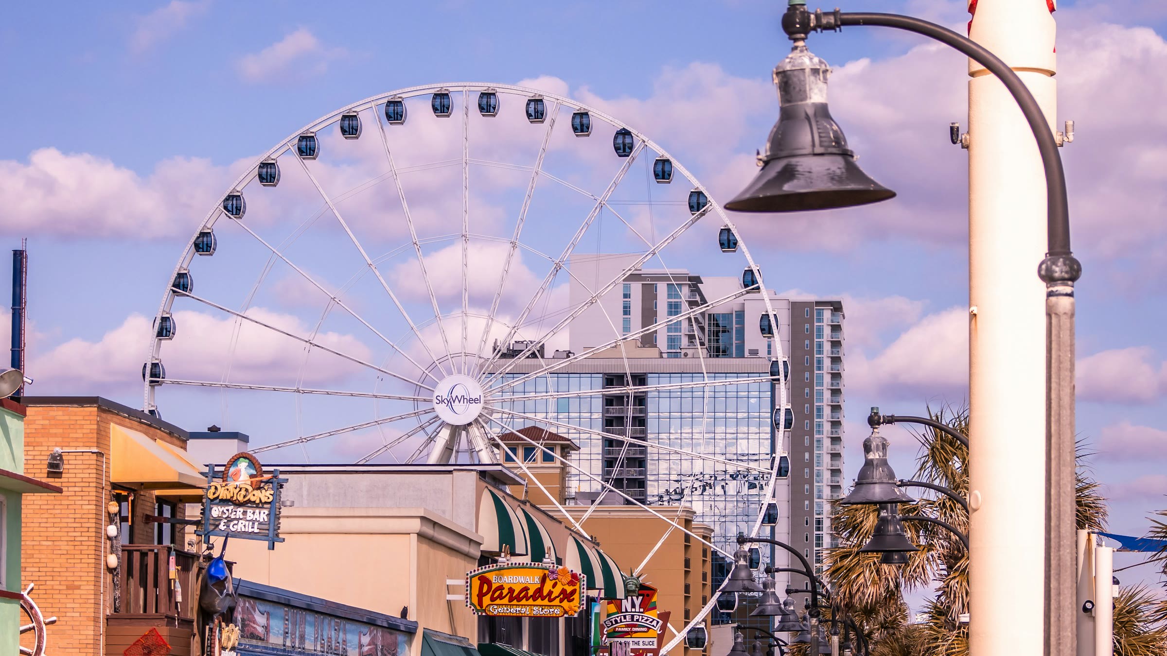 The Myrtle Beach SkyWheel rising above Boardwalk storefronts and lamp posts