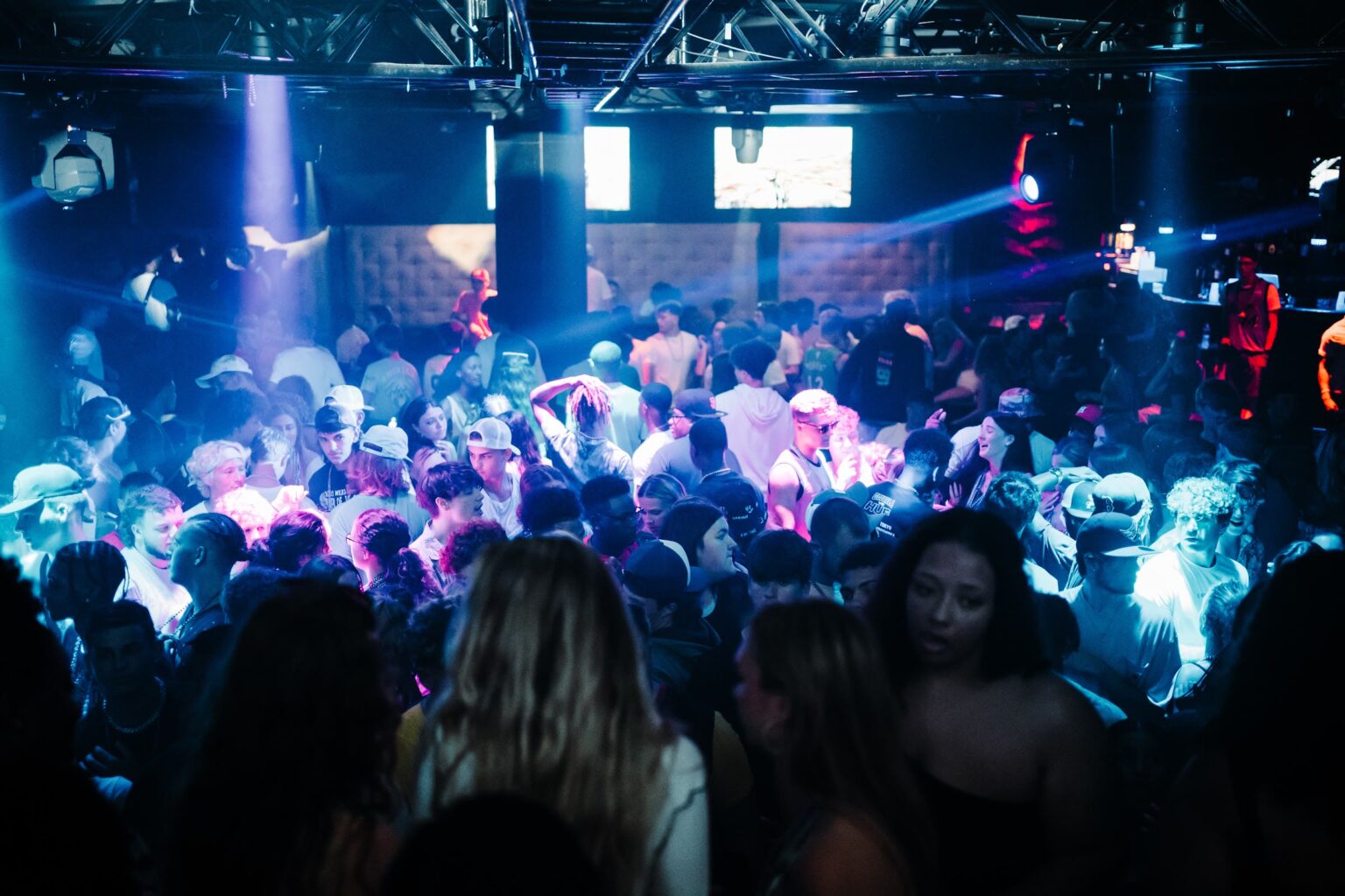 Packed dance floor of grads under blue and pink club lights at a Myrtle Beach Senior Week party